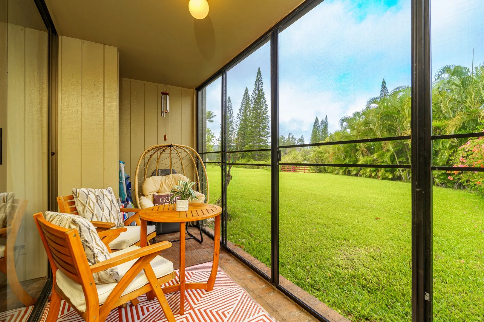 Screened lanai with hanging egg chair and teak furniture at Turtle Bay Hale vacation rental
